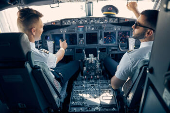 Back view portrait of professional pilot working in the passenger aircraft